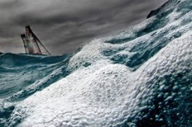 A sailing boad fighting agains the rouch sea and the waves at the America's Cup Final.
